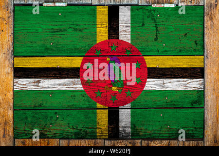 National flag of Dominica on a wooden wall background.The concept of national pride and symbol of the country.Flag painted on a wooden fence with meta Stock Photo