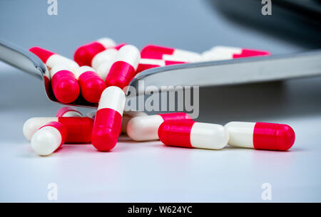 Red-white antibiotic capsule pills on stainless steel drug tray. Antimicrobial capsule pills. Pharmacy drugstore background. Pharmaceutics concept. Stock Photo