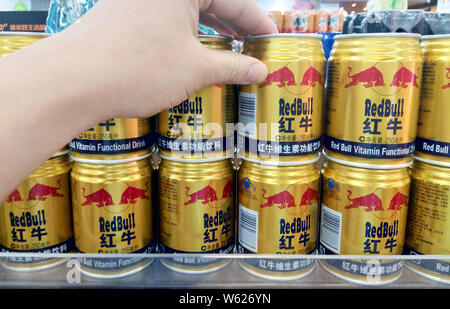 --FILE--A customer shops for cans of Red Bull energy drink on a shelf at a supermarket in Nanjing city, east China's Jiangsu province, 20 May 2018. Stock Photo