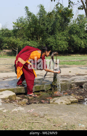 Woman drinking water from a water pump Stock Photo