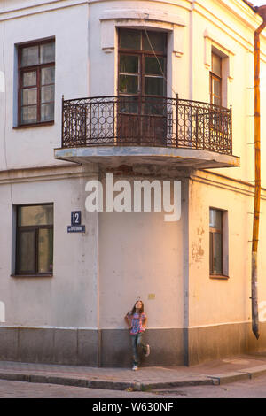 A girl walks on the street in front of the house. Vyborg Stock Photo