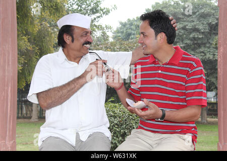 Man giving eyeglasses to his father and smiling Stock Photo