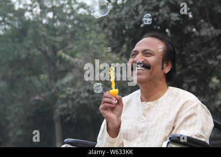 Man blowing soap bubbles and smiling Stock Photo