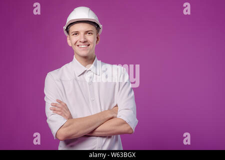young funny smiling man in white helmet on purple background Stock Photo