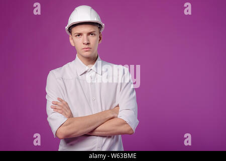 young serious man in white helmet on purple background Stock Photo