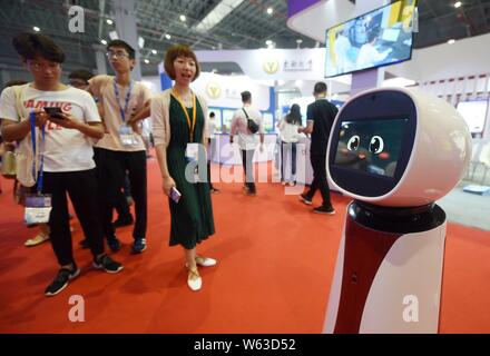 Chinese visitors view an intelligent robot on display during the 20th China International Industry Fair (CIIF 2018) in Shanghai, China, 19 September 2 Stock Photo