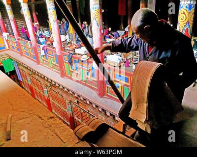 A worker displays printed pages at the Dege Sutra-Printing House, or Dege Parkhang ancient scripture printing house inside the Gengqing Monastery in t Stock Photo