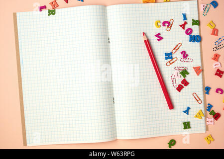 open checked notebook and red wooden pencil, back to school backdrop Stock Photo