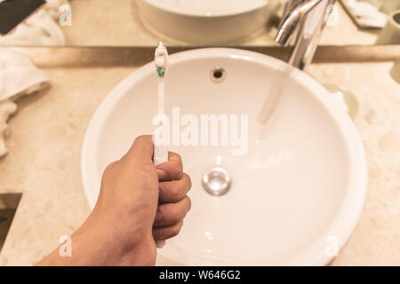 A man hand holding Toothbrush and toothpaste on the sink modern in bathroom. Stock Photo