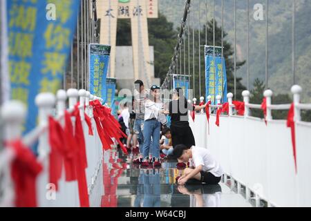 Tourists enjoy the scenery as they walk on the 60-storey-high glass-bottomed suspension bridge at the Taihuyuan scenic area in Lin'an district, Hangzh Stock Photo