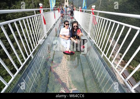 Tourists pose for photos on the 60-storey-high glass-bottomed suspension bridge at the Taihuyuan scenic area in Lin'an district, Hangzhou city, east C Stock Photo