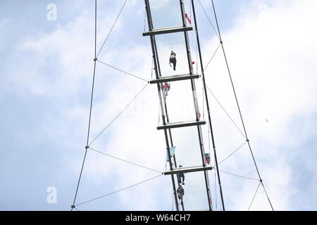 Tourists pose for photos on the 60-storey-high glass-bottomed suspension bridge at the Taihuyuan scenic area in Lin'an district, Hangzhou city, east C Stock Photo