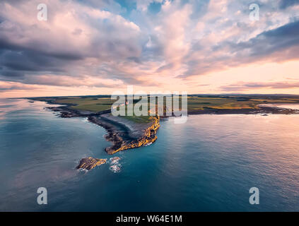 View from above on  Embleton bay, North sea, the cliff with seagulls, ruins and green agricultural fields. Sunset. England countryside. Northumberland Stock Photo