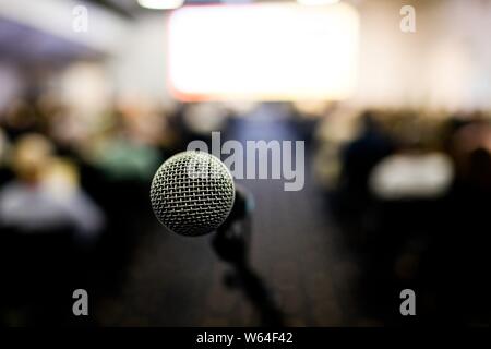 Front view on microphone on congress hall, people listening in the background Stock Photo