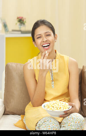Woman watching television and eating popcorn Stock Photo
