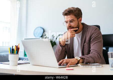 Portrait of focused young startup entrepreneur working with laptop in home office Stock Photo