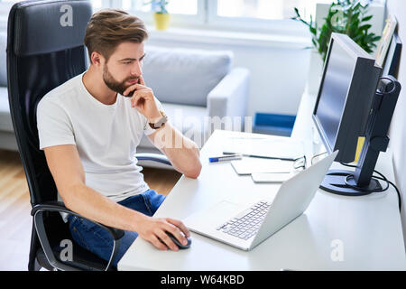 Thoughtful programmer, freelancer working from home office Stock Photo