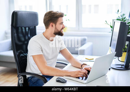 Happy student studying on laptop from his dorm room Stock Photo