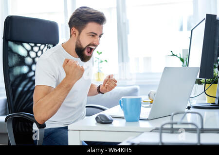 Successful man screaming excited working at home office Stock Photo