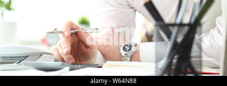 Hand of male clerk hold silver pen using calculator Stock Photo