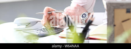 Hand of male clerk hold silver pen using calculator evaluating expenses Stock Photo