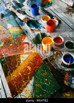colorful bright colors, brushes and abstract painting on newspaper background. cans of different colors and contemporary art Stock Photo