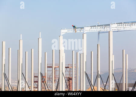 Industrial construction on site of new warehouse worker on top of high erected concrete columns and steel roof beams. Stock Photo