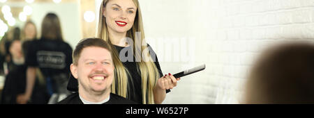 Young Hairdresser with Man Client in Beauty Salon Stock Photo