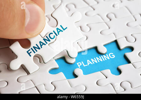 Hand holding piece of puzzle with words Financial Planning. Stock Photo