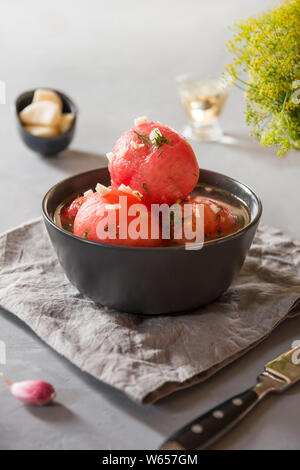 Marinated peeled tomatoes with garlic and dill, fresh ready to serve. Close up. Stock Photo