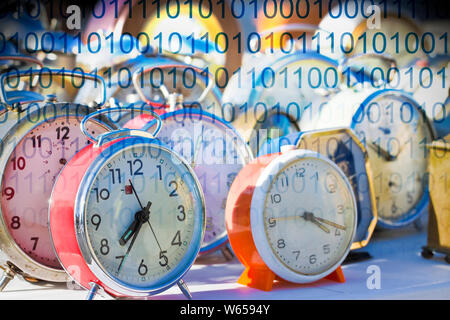 It's time to protect your data - Concept image with old colored metal table clocks with binary code Stock Photo