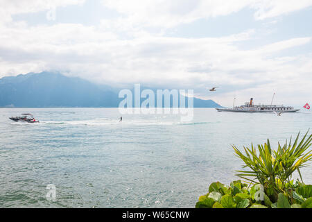 Summer fun activities of water skiing and steamboat cruising on Lake Geneva (lac Leman) in Swiss Montreux Riviera, Vaud, Switzerland during hot summer Stock Photo