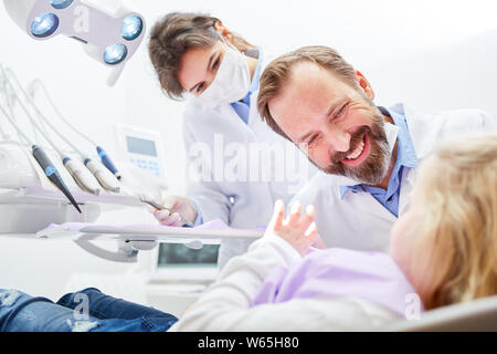 Friendly pediatric dentist and medical assistant take care of a child as a patient Stock Photo