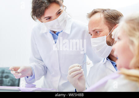 Dentist and dental assistant treat together a child as a patient in the dental clinic Stock Photo