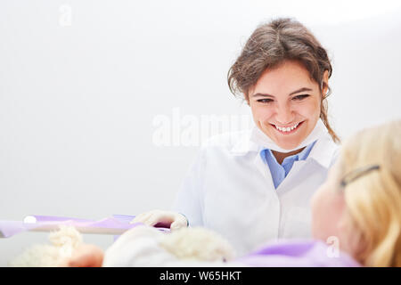 Friendly dentist or medical assistant and a child as a patient talking to the treatment Stock Photo