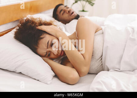 Unhappy woman having sleepless night with snoring man Stock Photo