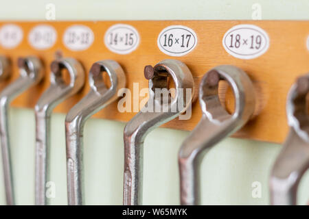 collection of spanners hanging on the wall on a wooden holder Stock Photo