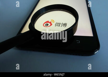 --FILE--A Chinese netizen looks at a logo of Weibo, the Twitter-like microblogging service of Chinese Internet portal Sina, on his smartphone in Ji'na Stock Photo