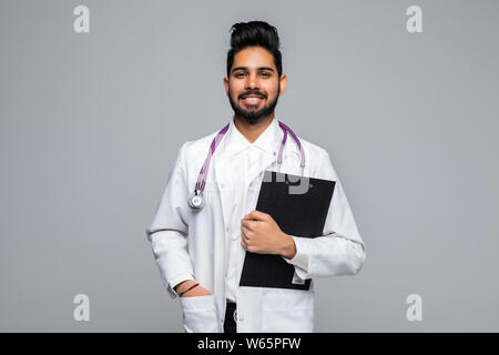 Portrait of a cheerful Indian male doctor holding a medical chart over light gray background Stock Photo