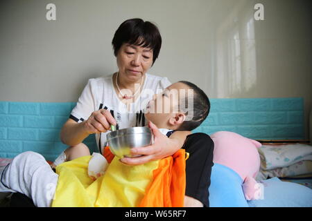 Chinese care worker Zhang Xia looks after the 7-year-old boy Peng Peng who was seriously injured due to his stepmother's cruel treatment at a hospital Stock Photo