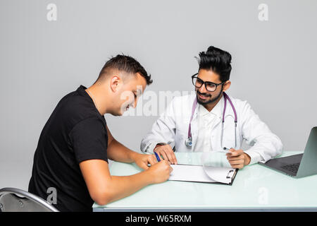 Patient signs a document with his doctor in medical office Stock Photo