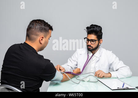 Doctor Holding Dial While Measuring Man's Blood Pressure Stock Photo