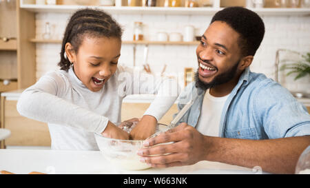 Excited afro girl playing with dough in kitchen Stock Photo