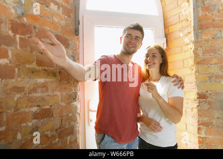 Young couple doing apartment repair together themselves. Married man and woman doing home makeover or renovation. Concept of relations, family, love. Talking about future design, caddling, look happy. Stock Photo