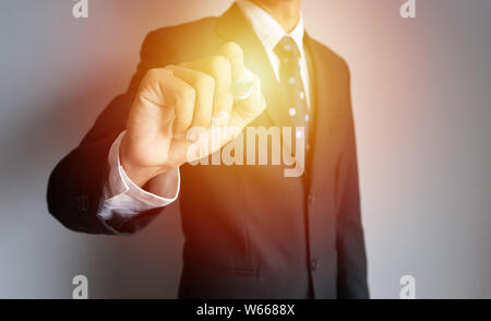 businessman hand holding black magic pen write something with virtual blank transparent whiteboard screen with copy space, light effect at pen Stock Photo
