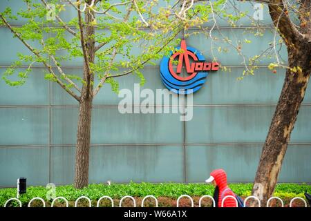 --FILE--A pedestrian walks past the headquarters of China National Offshore Oil Corporation (CNOOC) in Beijing, China, 4 April 2018.   China National Stock Photo