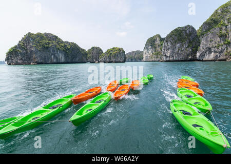 Green and orange empty plastic sea kayaks on water in Halong bay, Vietnam Stock Photo
