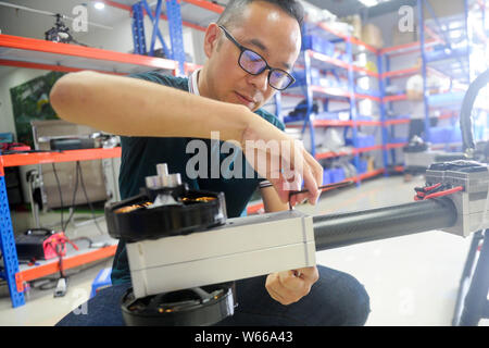 40-year-old Chinese man Zhao Deli dressed in protective suit check his homemade 'flying motorcycle' at his workshop in Tangxia town, Dongguan city, so Stock Photo