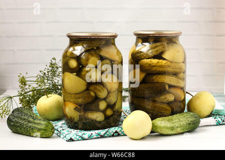 Marinated cucumbers with apples in jars are arranged on a white background, Harvest for the winter, close-up, horizontal photo Stock Photo