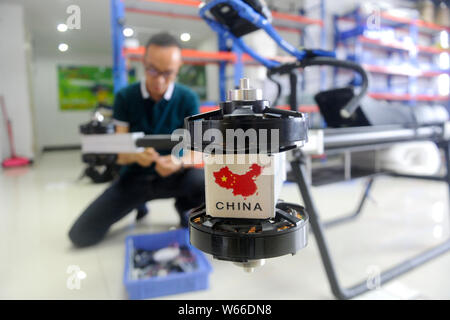 40-year-old Chinese man Zhao Deli dressed in protective suit check his homemade 'flying motorcycle' at his workshop in Tangxia town, Dongguan city, so Stock Photo